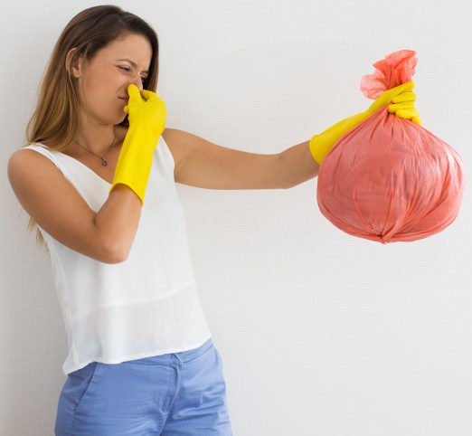 Unhappy woman holding trash with disgusting smell