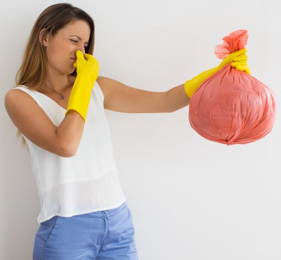 Unhappy woman holding trash with disgusting smell