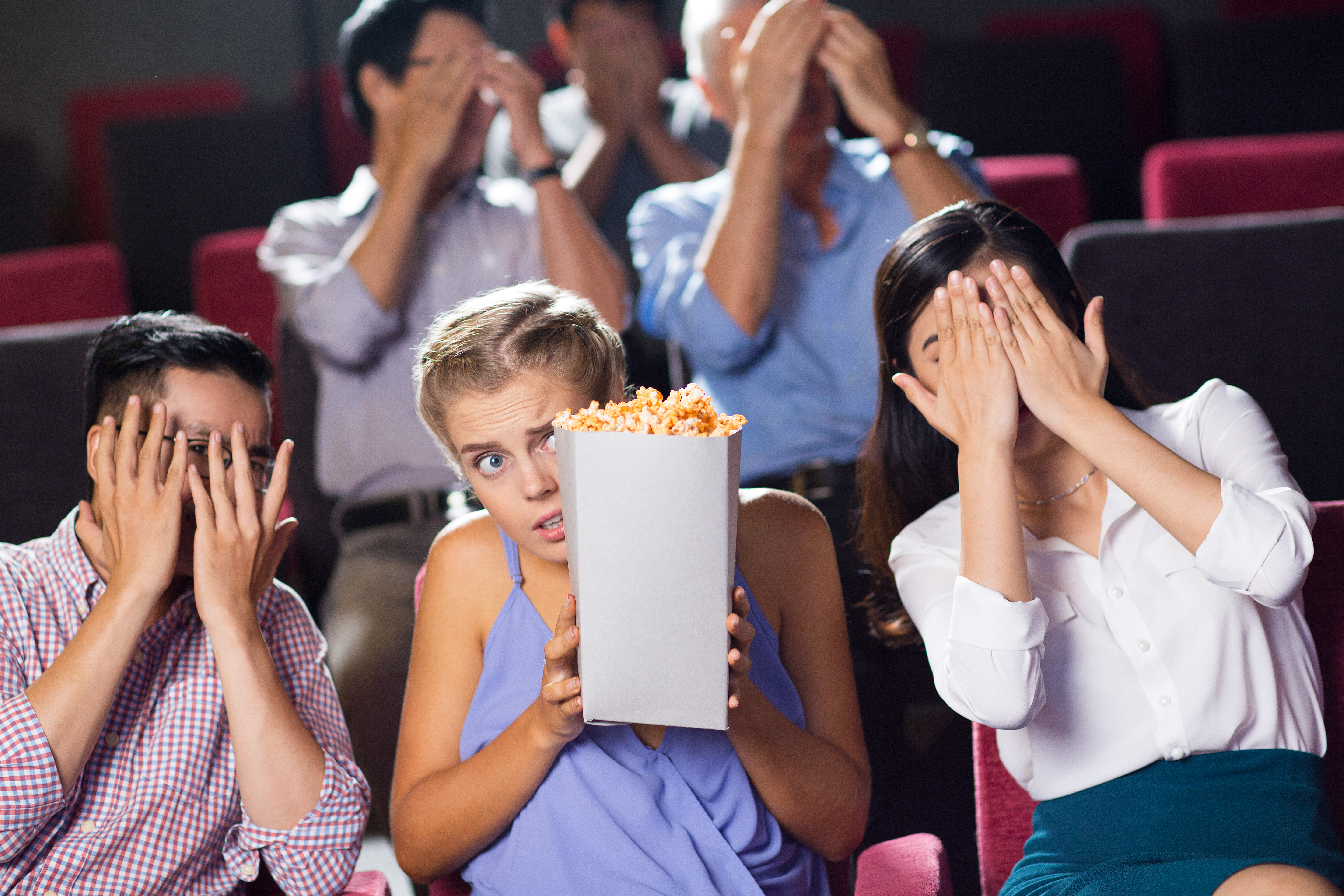 Terrified friends watching horror movie in cinema