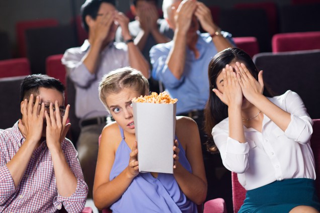 Terrified friends watching horror movie in cinema